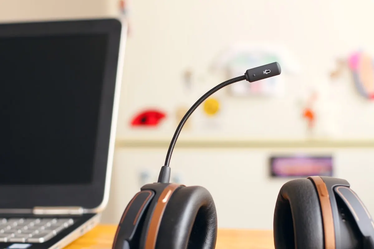 Headset de atendimento ao lado de um notebook em mesa de suporte